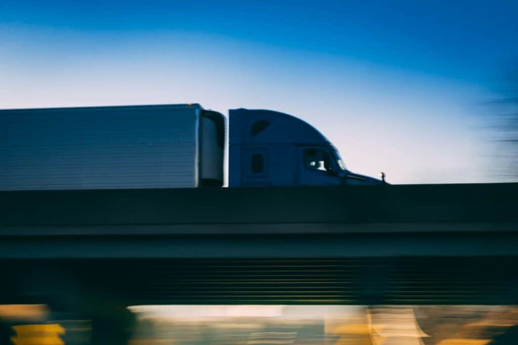Semi truck driving fast over a bridge