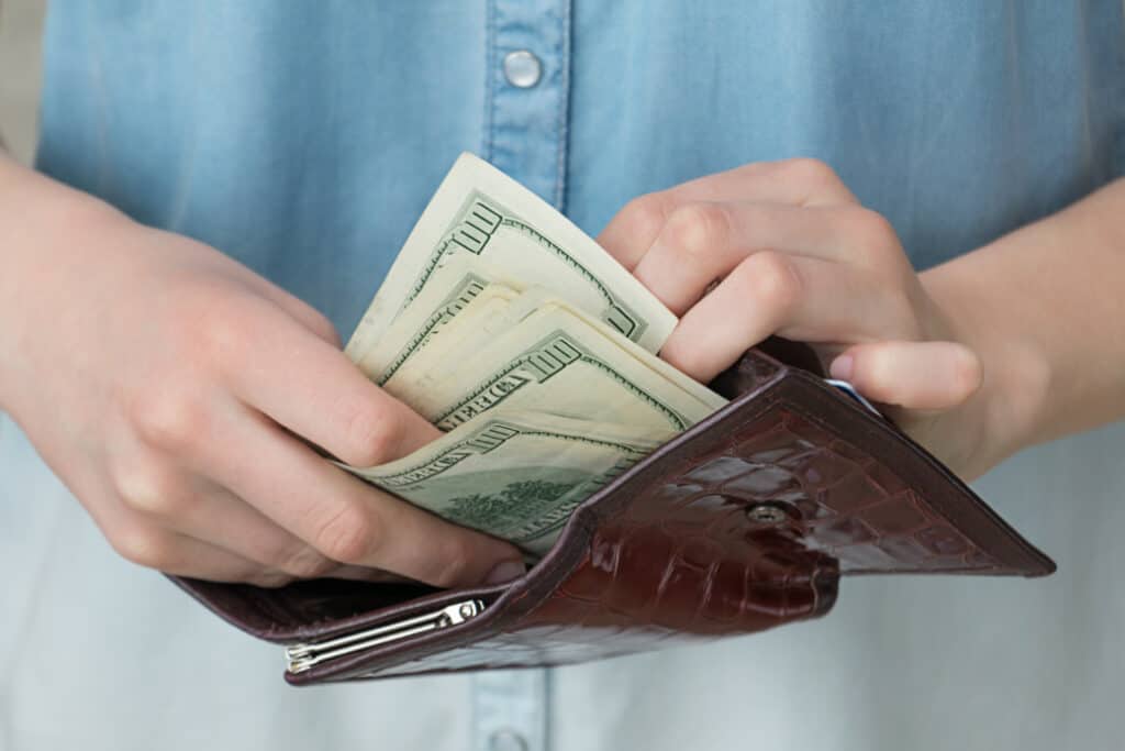 girl putting $100 bill into wallet